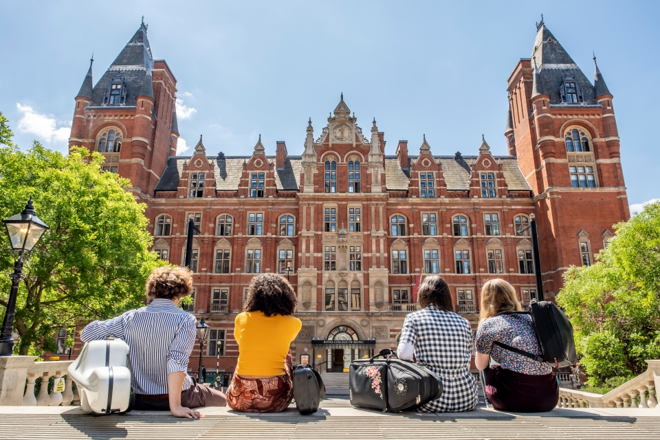 Four students sitting outside the main RCM building 